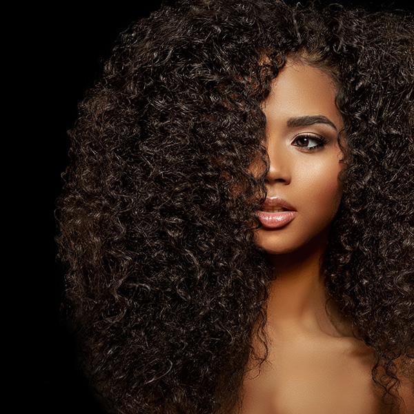 A woman with voluminous, curly hair and makeup.