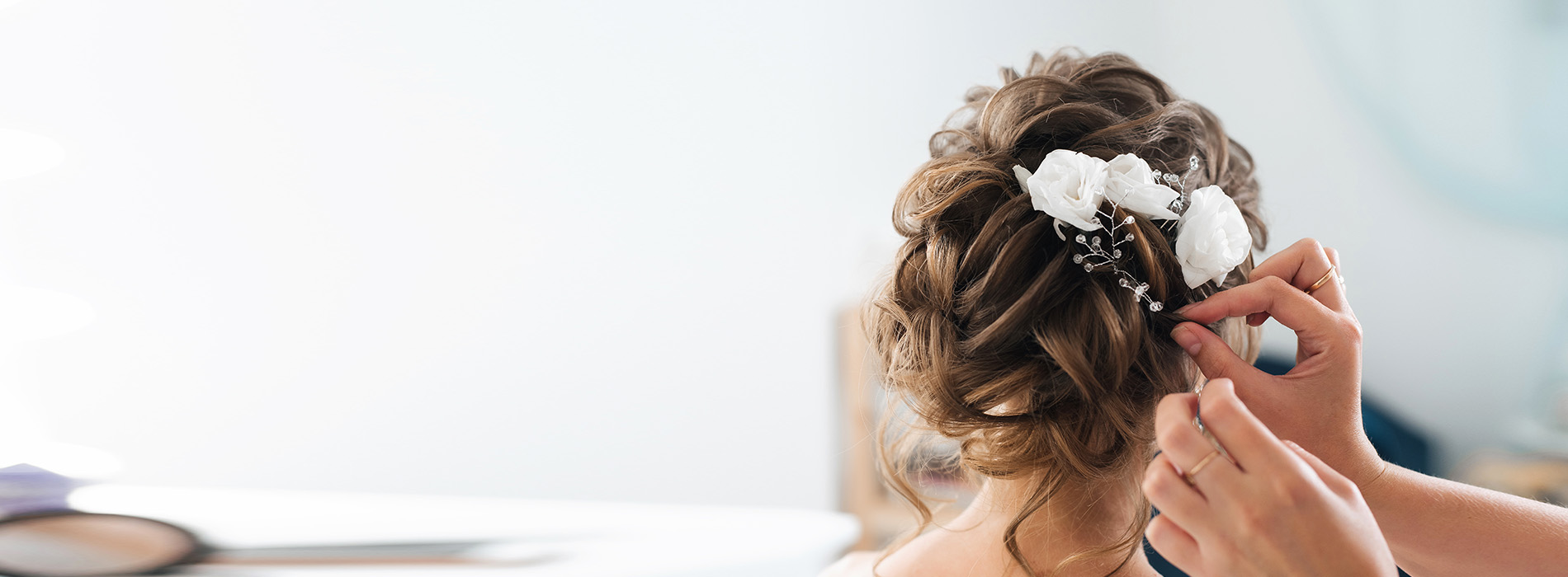A person styling hair with a curler, focusing on the task at hand.